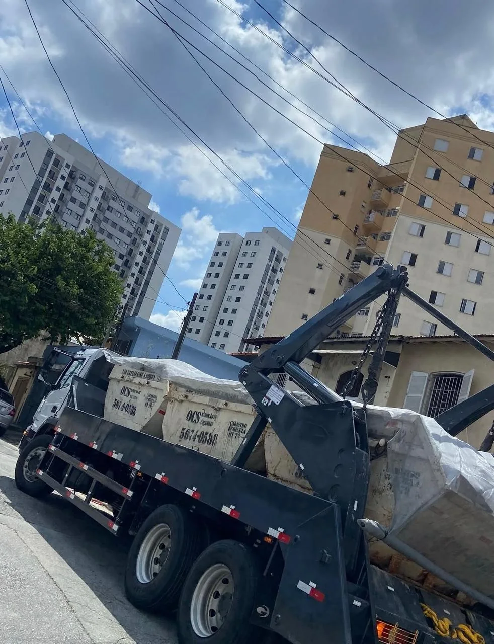 Caminhão transportando caçambas em área urbana